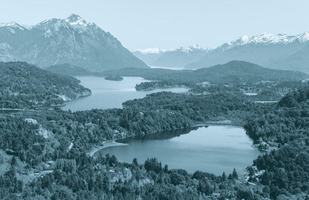 Foto aérea de un paisaje patagónico. Un valle boscoso entre montañas, con lagunas en el medio.